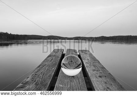 Glass Ball On A Wooden Pier At A Swedish Lake At Dusk In Black And White. Nature Shot From Scandinav