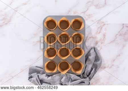 Flat Lay. Scooping Dough Into The Cupcake Pan Lined With Parchment Muffin Liners To Bake Sharlotka M