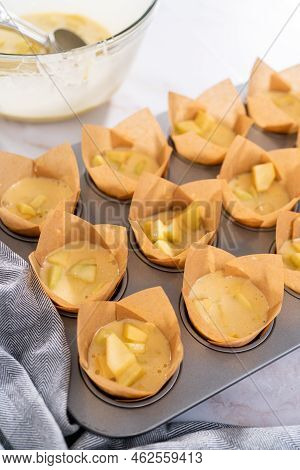 Scooping Dough Into The Cupcake Pan Lined With Parchment Muffin Liners To Bake Sharlotka Muffins.