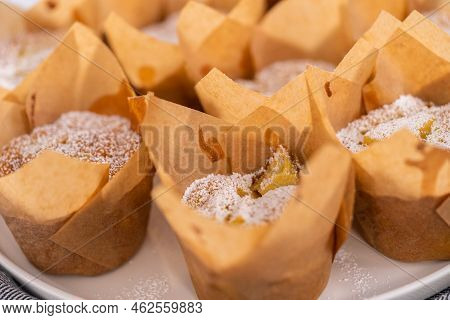 Freshly Baked Apple Sharlotka Muffin Dusted With Powdered Sugar On A White Plate.