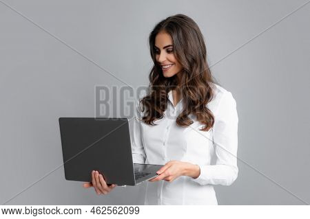 Beautiful Smiling Business Woman Over Grey Background Using Laptop Computer.