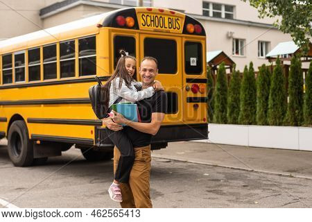 Parent Taking Child To School. Pupil Of Primary School Go Study With Backpack Outdoors. Father And S