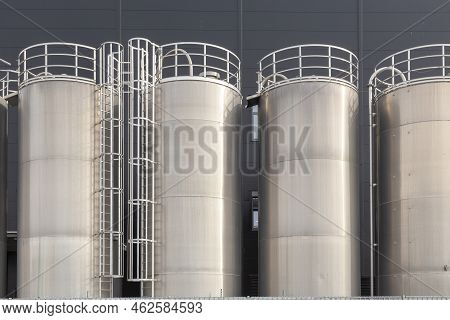 Detail Of Chrome Silos In Front Of Generic Grey Wall Of A Plant