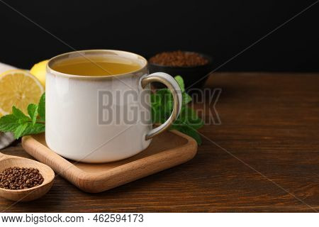 Cup Of Aromatic Buckwheat Tea And Granules On Wooden Table, Space For Text