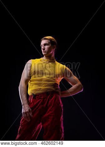 A Young Muscular Man In A Bright Outfit Poses In A Pretentious Pose, Style And Grotesque. Attractive