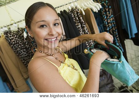 Porträt einer lächelnden jungen Frau mit Handtasche in der boutique