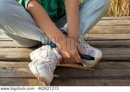 Woman Sitting On The Wooden Pier Over The River Outdoors And Holding E-cigarette In  Hand Before Smo