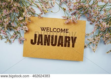 Welcome January Written On Paper Card With Flower Frame Decoraton On Pink Background