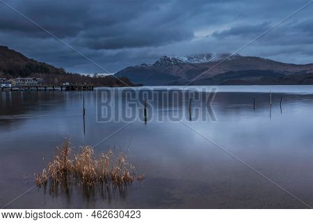 Stunning Landscape Image Of Loch Lomond And Snowcapped Mountain Range In Distance Viewed From Small 
