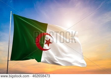 Algeria National Flag Waving In Beautiful Clouds. Algeria Flag Realistic Waving For Design On Indepe