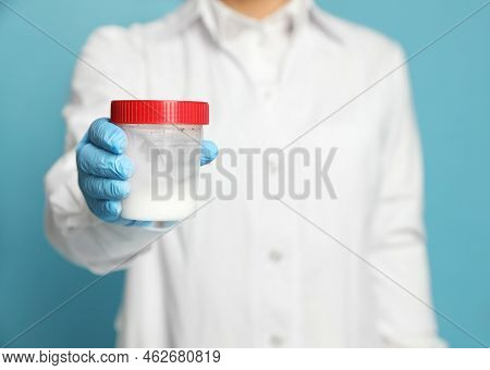 Scientist Holding Container With Sperm On Turquoise Background, Closeup. Space For Text