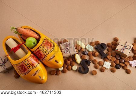 Saint Nicholas - Sinterklaas Day With Shoe, Carrot And Traditional Sweets On Caramel Background