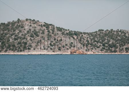 Small Greek Island Covered With Small Vegetation During A Sunny Summer Day.