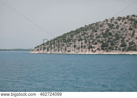Small Greek Island Covered With Small Vegetation During A Sunny Summer Day.