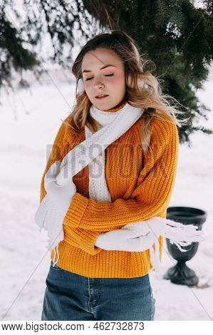Teen Blonde In A Yellow Sweater Outside In Winter. A Teenage Girl On A Walk In Winter Clothes In A S