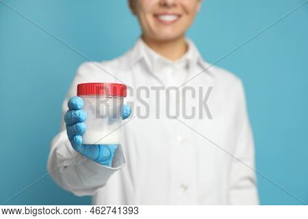 Scientist Holding Container With Sperm On Turquoise Background, Closeup. Space For Text
