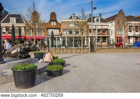 Purmerend, Netherlands - March 31, 2021: Cow Sculpture And Historic Houses On The Koemarkt Square In