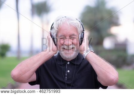 Portrait Of Smiling Senior Man Enjoying Listening Music By Headphones. Caucasian Bearded Elderly Gra
