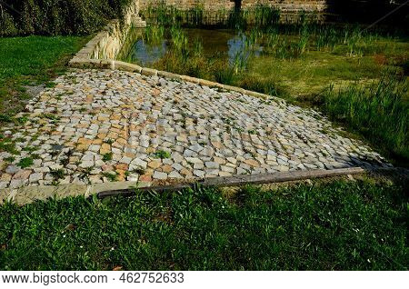 Restoration Of A Pond With A Stone Wall Buried Under The Terrain. Fire Tank With Beveled Stone Paved