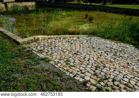 Restoration Of A Pond With A Stone Wall Buried Under The Terrain. Fire Tank With Beveled Stone Paved
