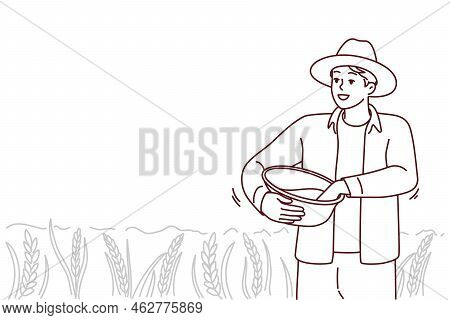 Male Farmer Working In Field On Harvest Season. Smiling Man Busy With Agriculture On Pasture Or Crop