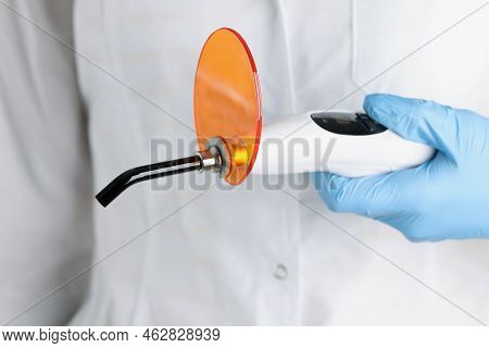 The Doctor Is Holding Dental Curing Light, Close-up. Instruments For Prosthetics Fillings, Solidify 