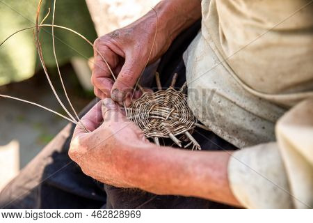 Hands Of The Senior Craftsman While Weaving Wicker Basket. Traditional Slovak Folk Craft.