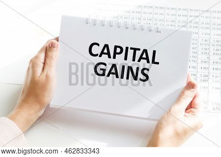 Capital Gains Text On A Notebook In The Hands Of A Businessman On The Background Of An Office Desk, 