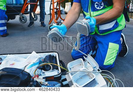 Ambulance Paramedic Holding Defibrillator Pads In Hands While Resuscitation Casualty Outdoors Near A