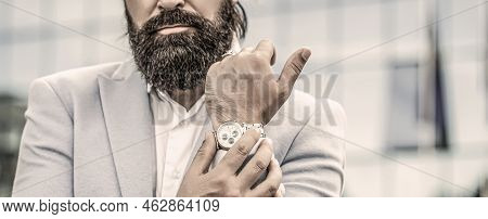 Portrait Successful Businessman In A Business Suit, Using The Watch On A City Background. Watch In A