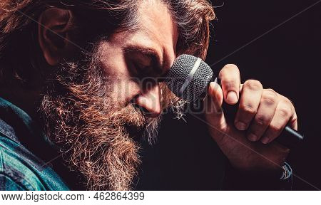 Man With A Beard Holding A Microphone And Singing. Bearded Man In Karaoke Sings A Song Into A Microp