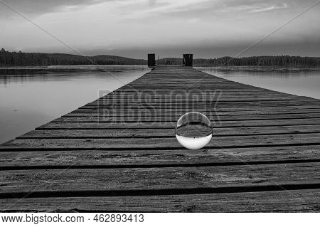 Glass Ball On A Wooden Pier At A Swedish Lake At Dusk In Black And White. Nature Shot From Scandinav