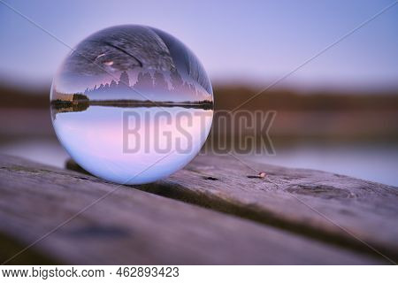 Glass Ball On A Wooden Pier At A Swedish Lake At Evening Hour. Nature Shot From Scandinavia