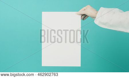 Blank Paper Board In Woman's Hand.she Wear White Latex Glove Andppe Suit On Green Mint Or Tiffany Bl