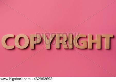 Word Copyright Made Of Wooden Letters On Dark Pink Background, Flat Lay. Plagiarism Concept