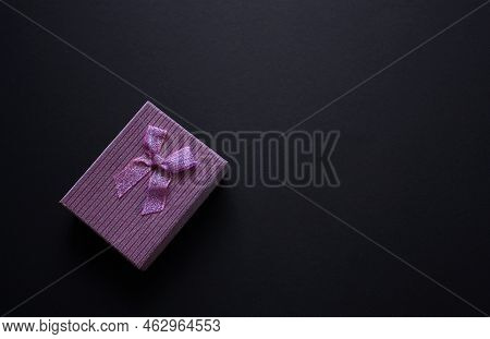 Single Festive Violet Gift Box With Small Shiny Bow. Black Background. Metallised Box Cover. Wrappin