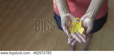 Adult Hands Holding Yellow Gold Ribbon, Sarcoma Awareness, Bone Cancer, Cancer Awareness. Woman Hold