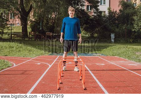 Blond Boy In Sportswear Jumps Over Red Obstacles To Improve Lower Body Dynamics. Plyometric Training