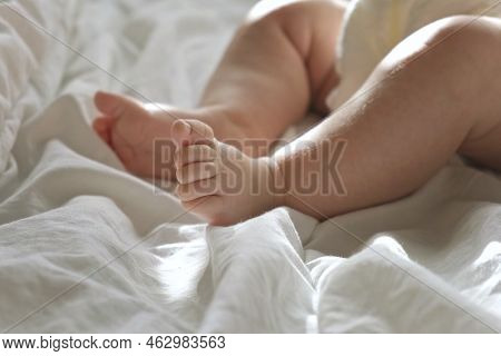 Baby Legs Close Up On White Blanket. Healthy Newborn Feet. Warm Sunlight. Beautiful Shot Of Infants 