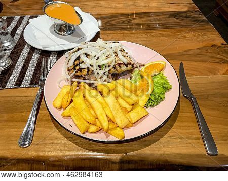 A Greek Dish With A Variety Of Meats, Chips And Onions.