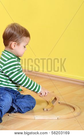 Cute caucasian toddler playing with toy train in kindergarten. Extra text space on upper right corner.