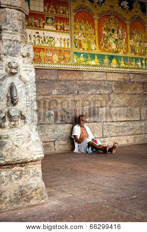 indian man pilgrim resting inside ancient colonnade of Meenakshi Temple