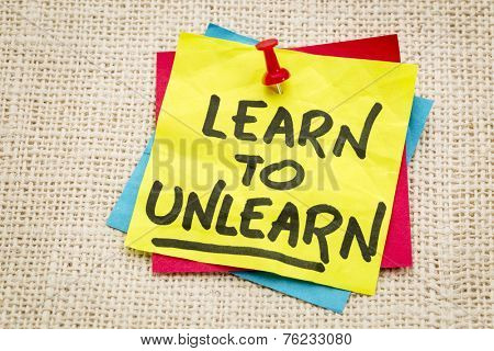 learn to unlearn - advice or motivation words on a sticky note against burlap canvas