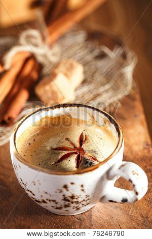 A cup of spiced coffee with anis star and cinamon sticks and sugar