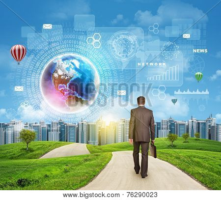 Businessman walks on road. Rear view. Buildings, grass field and sky with virtual elements