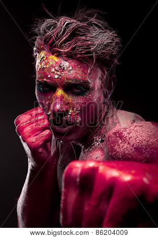 A creepy portrait of man with red body art.
