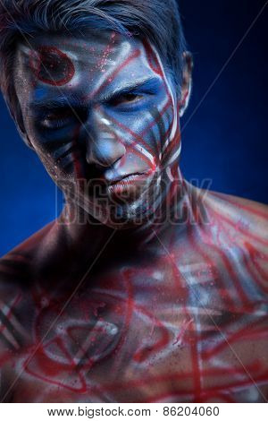 A creepy portrait of a halloween man with face art.