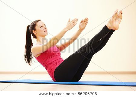 young female instructor doing stretching pilates exercises in sport club