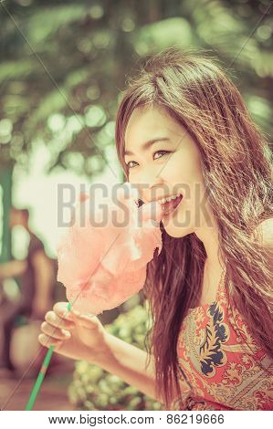 Cute Thai Girl Is Eating Pink Candyfloss With Joy In Vintage Color.