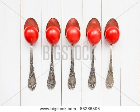 Red Easter Eggs In Old Spoons On White Wooden Background